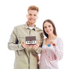 Poster - Young couple with house model and key from their new home on white background