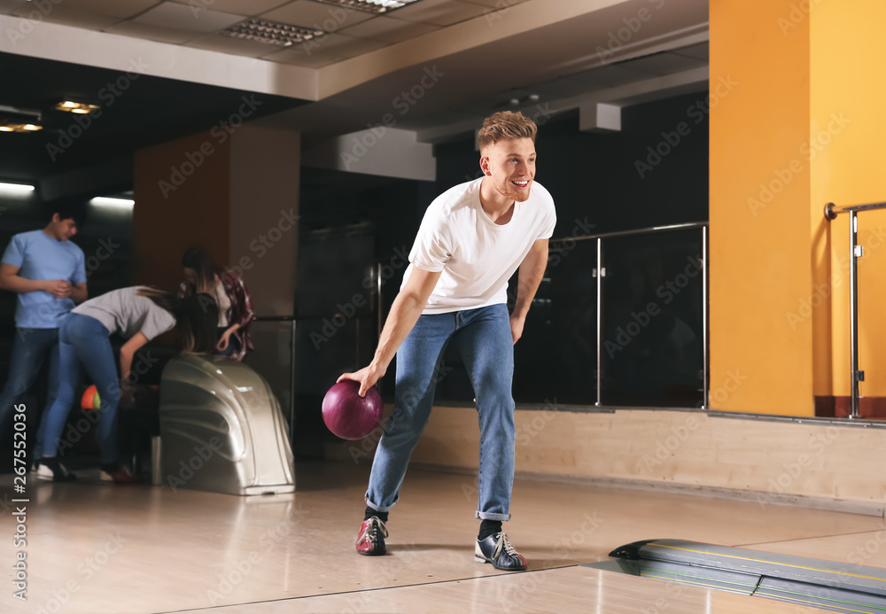 Young man playing bowling in club