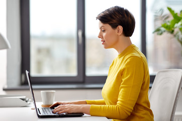 business, technology and people concept - businesswoman with laptop computer working at office