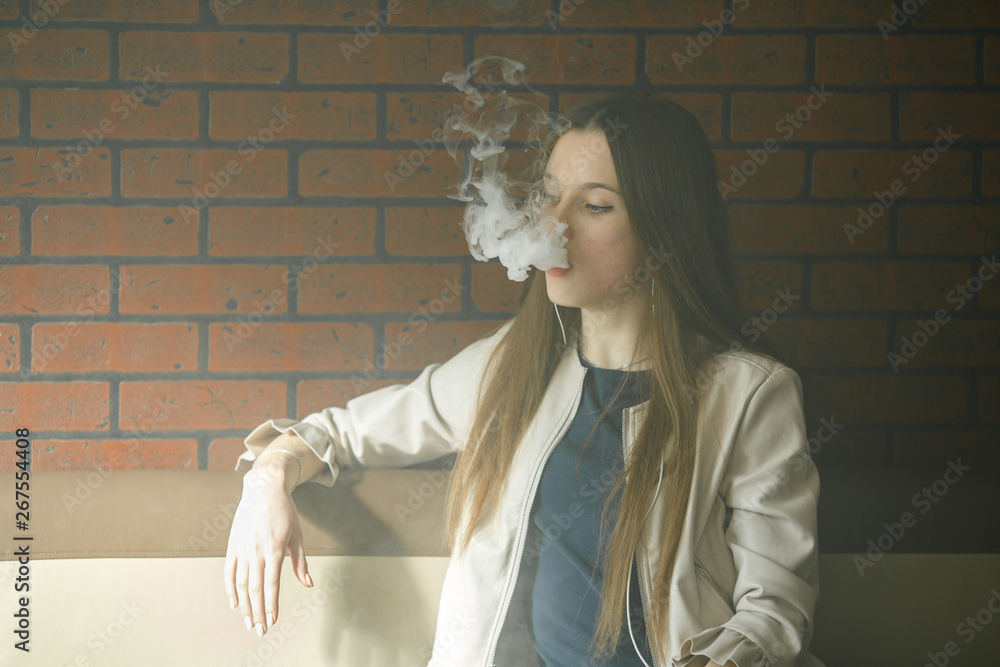Vaping teenager. Young pretty white girl smoking an electronic cigarette in  vape bar. Bad habit. Stock Photo