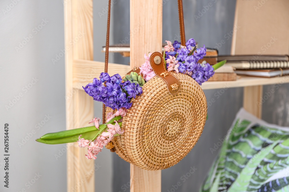 Wicker bag with beautiful hyacinth flowers hanging on shelf