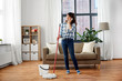 © Syda Productions - people, housework and housekeeping concept - happy asian woman with mop cleaning floor and calling on smartphone at home
