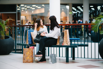 Wall Mural - Beautiful young mom and teenage daughter are holding shopping bags and smiling while doing shopping in mall. Family shopping.