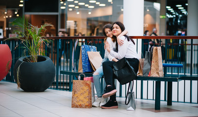 Wall Mural - Beautiful young mom and teenage daughter are holding shopping bags and smiling while doing shopping in mall. Family shopping.