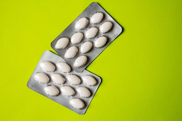 blister with white pills on green background with copyspase