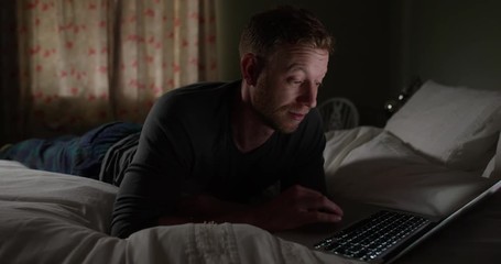 4K Man in bedroom surfing the net at night & looking at screen with surprised expression