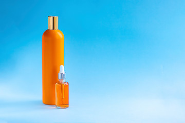 two mockup orange bottle with oil on blue background. Beauty and cosmetics concept about Slim body and Sun screen, health care skin, hair protection, UV filter. Horizontal with copy space