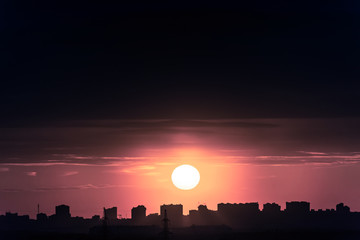 Wall Mural - twilight sunset sky in the city. a huge sun behind the silhouette of buildings.