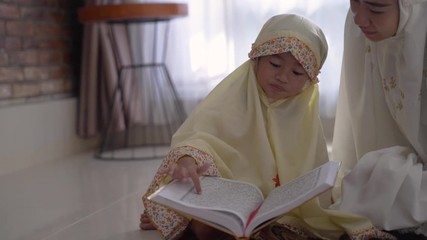 Wall Mural - muslim parent and daughter reading quran after praying together