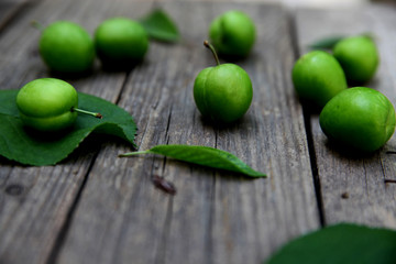 Green fresh plums on the wooden background