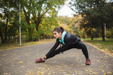 Wall Mural - Pretty fitness woman outdoors in the park make exercises.