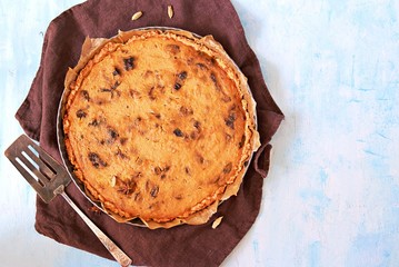 Wall Mural - Whole pumpkin pie with prunes in a baking dish on a light blue background