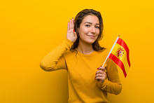 Young European Woman Holding A Spanish Flag Trying To Listening A Gossip.