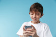 © Drobot Dean - Image of joyful caucasian boy 10-12y with freckles wearing white casual t-shirt smiling and holding smartphone