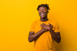 © Asier - Young black man wearing rastas over yellow background laughing keeping hands on heart, concept of happiness.
