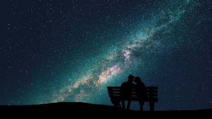 Wall Mural - The man and woman sitting on a bench on the starry sky background. time lapse