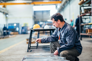 Mature man working with measuring instrument at the factory.