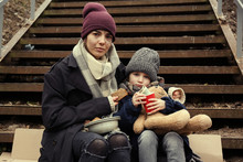 Poor Mother And Daughter With Bread Sitting On Stairs Outdoors