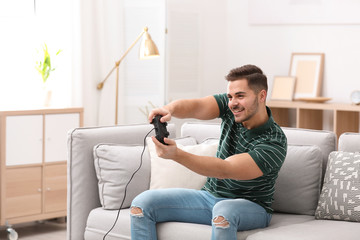 Emotional young man playing video games at home