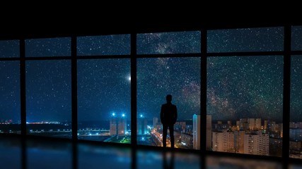 Wall Mural - The man standing near a window on the city with stars background. time lapse