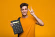 © Asier - Young student man holding a calculator looking sideways with doubtful and skeptical expression.