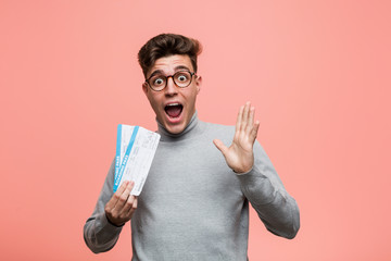 Wall Mural - Young cool man holding an air tickets celebrating a victory or success