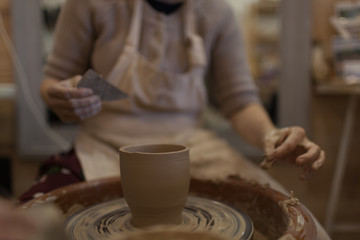 Potter working on potters wheel making ceramic pot from clay in pottery workshop