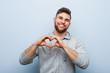 © Asier - Young handsome fitness man smiling and showing a heart shape with him hands.