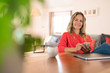 © Westend61 - Portrait of smiling woman with laptop and cell phone on dining table at home