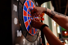 Close-up Of Tattooed Man Taking Out Darts From Electronic Dartboard