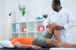 © Viacheslav Yakobchuk - Sportsman in orange t-shirt having examination of leg after trauma