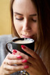 © Kiryl Lis - Attractive girl with long hair holding cup of cappuccino and drinking coffee in the cafe. Closeup portrait.