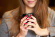 © Kiryl Lis - Smiling girl with red nails holding a cup of coffee.