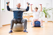 © Photographee.eu - Two elderly people holding weights and sitting on exercising balls