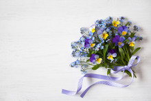 A Bouquet Of Forget-me-nots And Pansies On A Wooden Background
