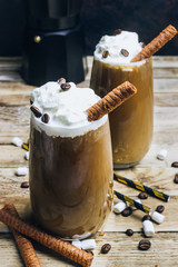 Ice coffee in a tall glass on a old rustic wooden table. Cold summer drink