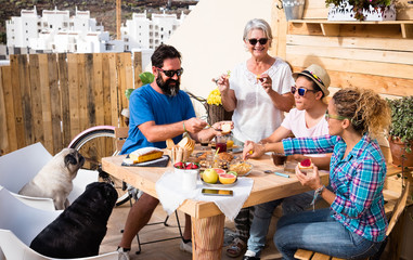 Happy group of family enjoying breakfast together. Four people, senior grandmother, teenager and parents. Wooden table. Two pug dogs.