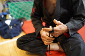 brazilian jiu jitsu bjj fighter using tape to strengthen taping his fingers at the tournament before