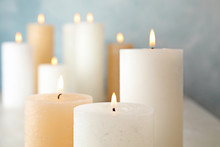Burning Candles On Table Against Color Background, Closeup