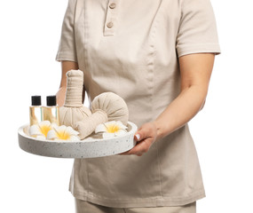 Professional masseuse in uniform holding tray with spa supplies on white background, closeup