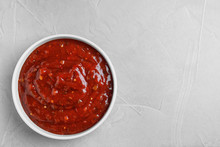 Bowl Of Hot Chili Sauce On Light Background, Top View. Space For Text