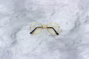 Stylish gold eyeglasses spectacles on marble background. Top view Copy space Minimal style