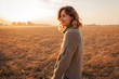 © Виталий Сова - Portrait of a beautiful young model in warm clothes enjoy day, on background field in  sunny autumn day . Autumn warm photo. Woman smiling and look away, joyful cheerful mood.
