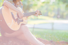 Woman Is Playing Acoustic Guitar In The Garden.