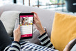 © weedezign - Woman lying down on sofa using tablet watching live blogger online at home.digital technology lifestyle