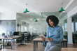 © mavoimages - Smiling businesswoman sitting on an office table using a tablet