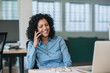 © mavoimages - Smiling businesswoman sitting at her desk talking on a cellphone