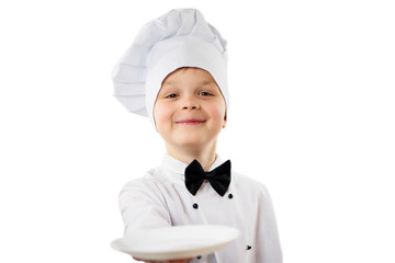 Wall Mural - cute funny boy chef in uniform holds a clean empty white plate in his hand