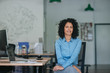© mavoimages - Smiling young businesswoman sitting at her desk in an office