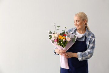 Wall Mural - Female florist with bouquet on light background